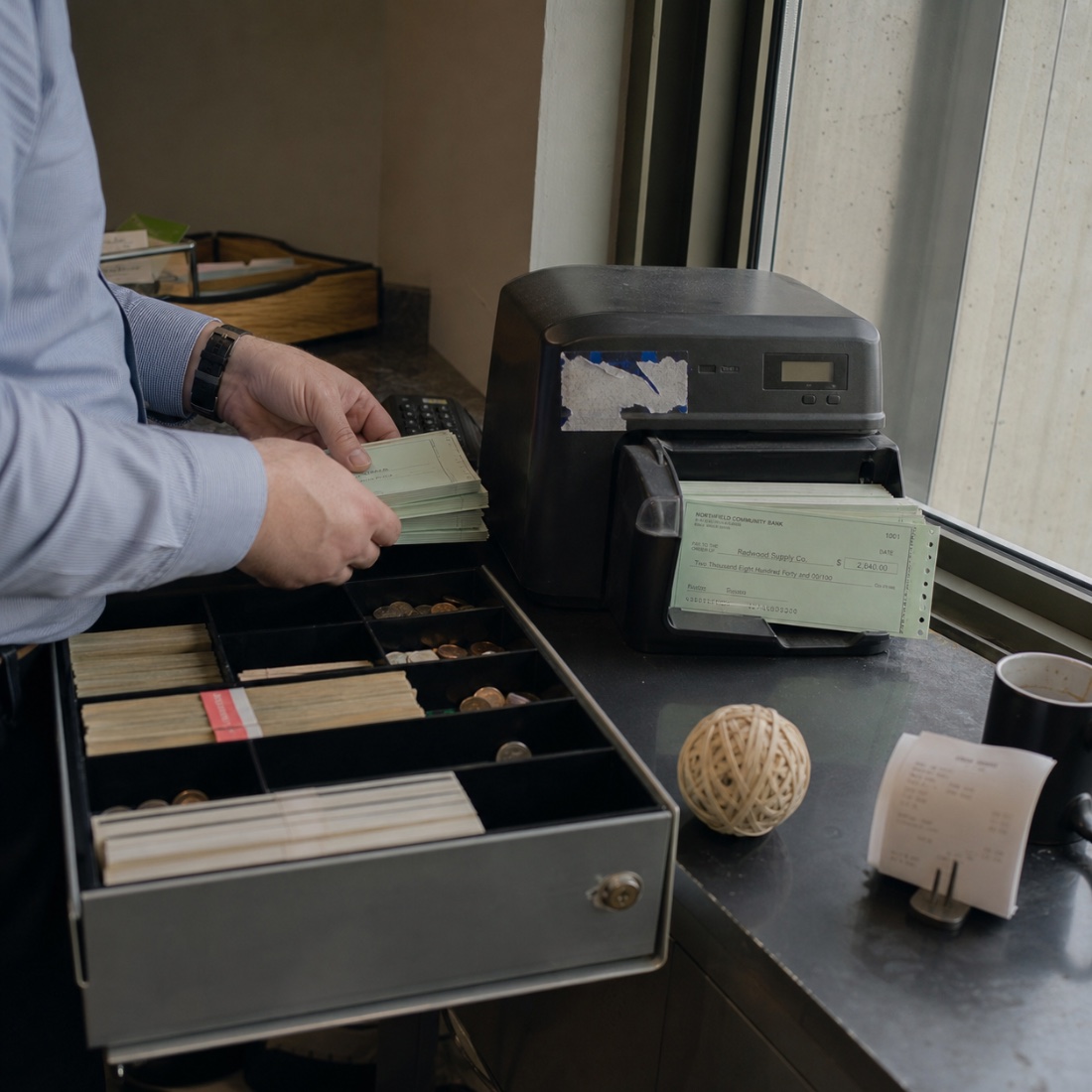 Printing vendor checks beside an open cash drawer
